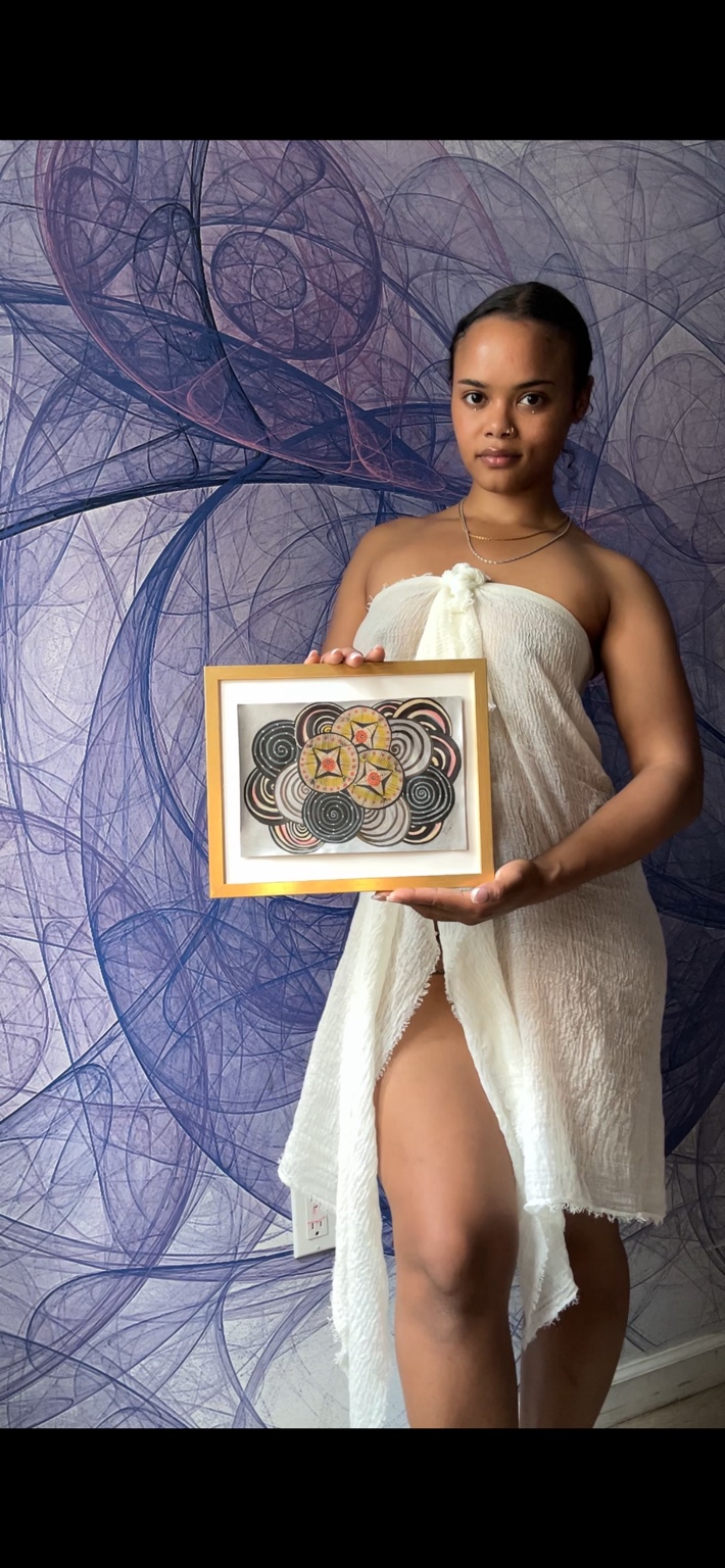 Miss Rey holding a framed original patterned artwork